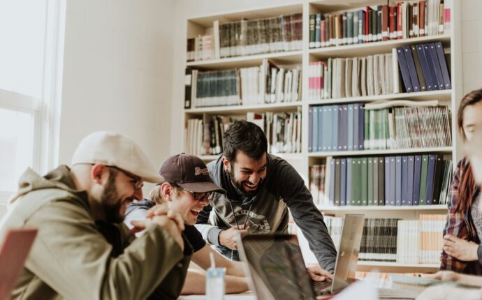 Étudiants en informatique travaillant ensemble sur ordinateurs dans un campus technologique moderne