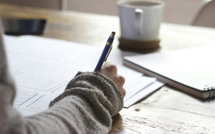 Candidat préparant un examen de certification professionnelle sur un bureau avec ordinateur et notes d'étude